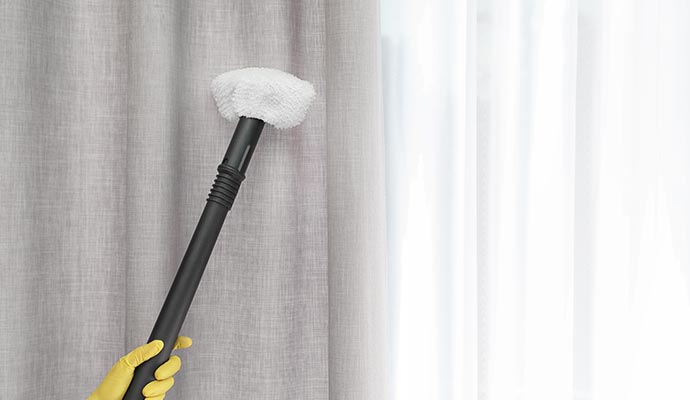 A person is cleaning a drapery with visible dirt