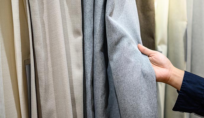 A person is inspecting cotton draperies